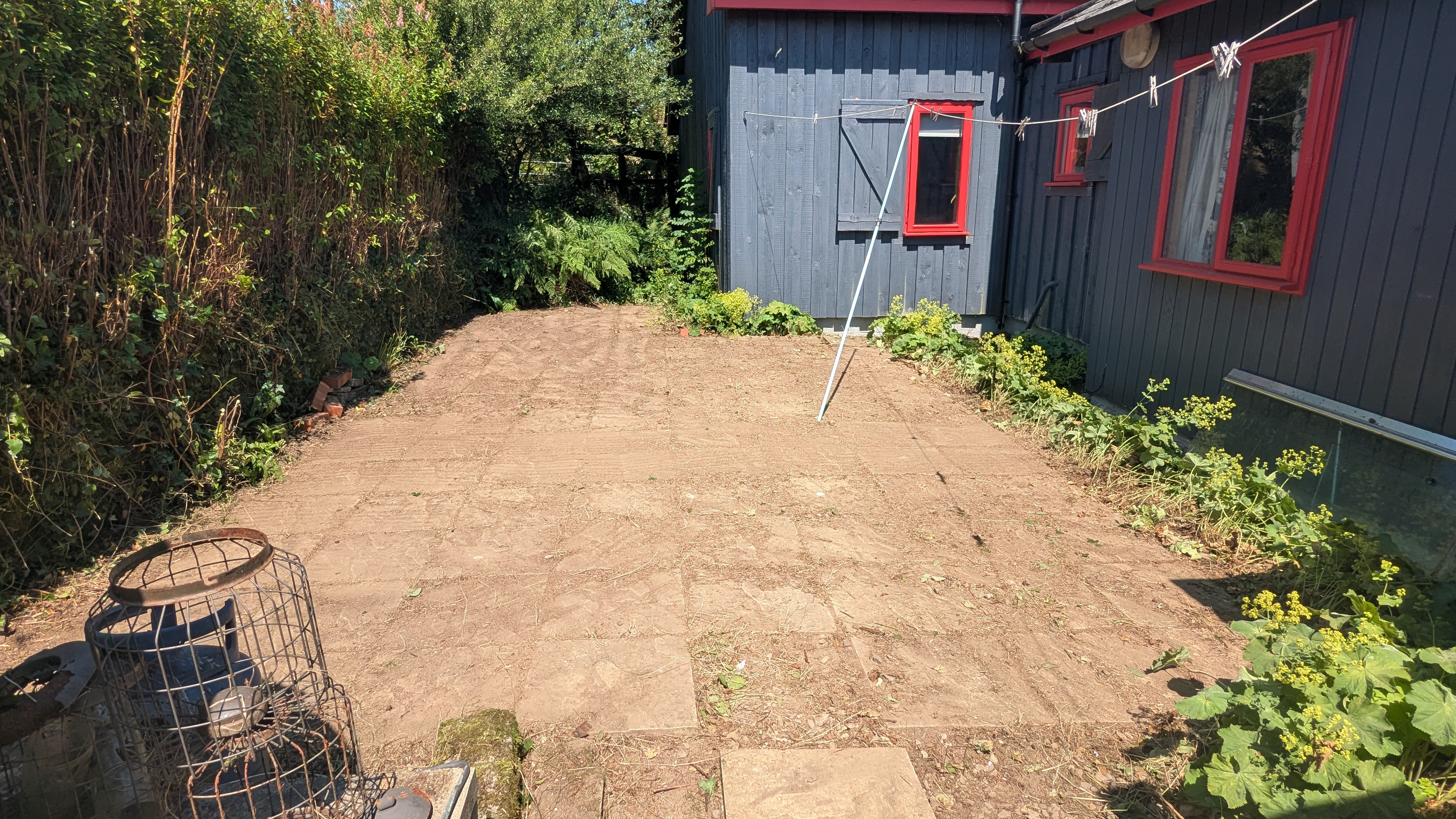 Cleared patio in Crymych swept back to bare stone slabs after removing lady's mantle and grass