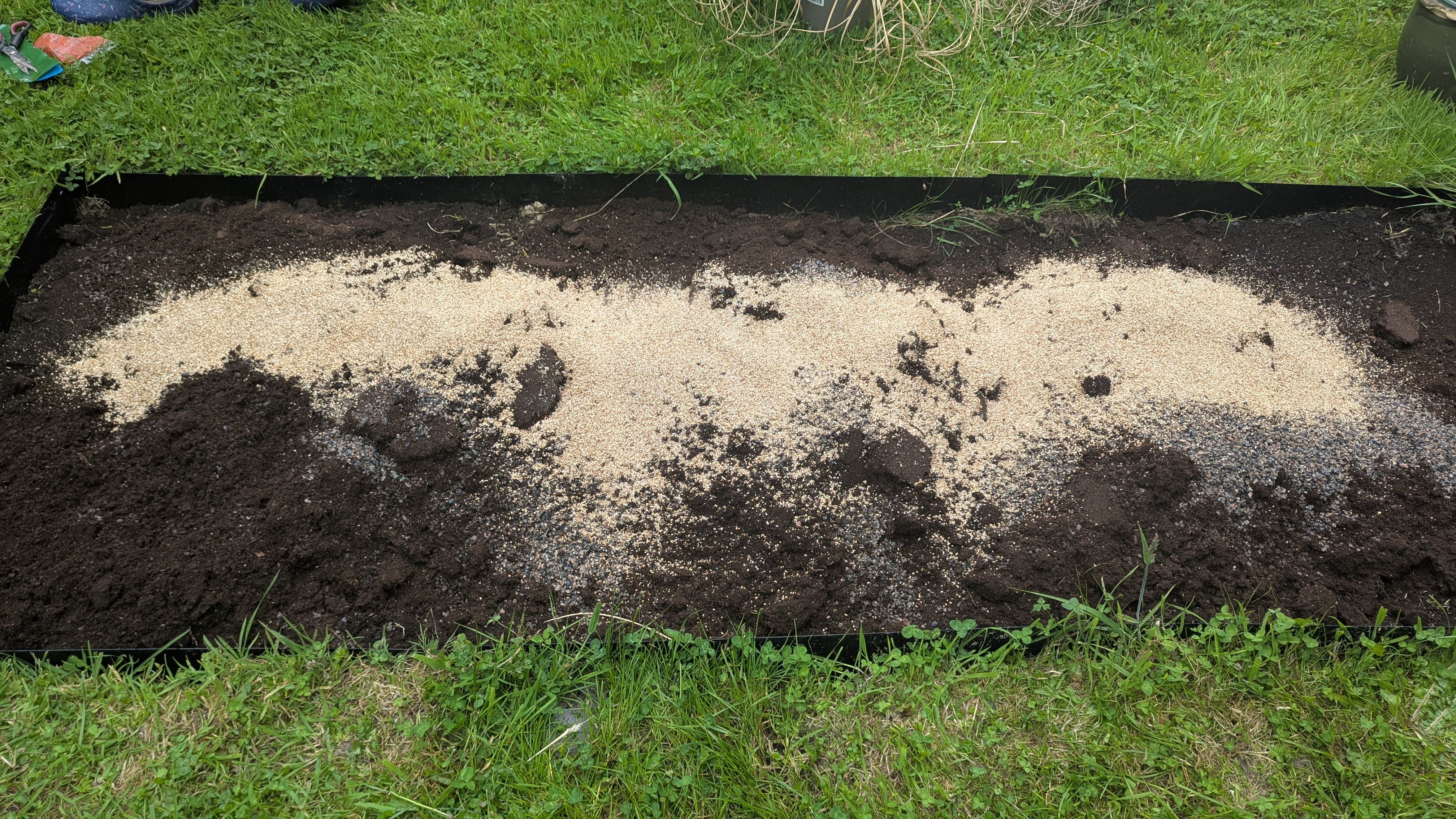 Perlite spread over the soil of a new planting bed in Llanfallteg, Whitland area, ready to be forked through